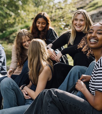 Glada ungdomar sitter tillsammans utomhus.