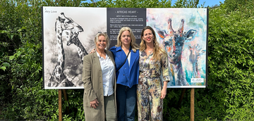 Karin Holmström och Jytte Fredholm Ferreira tillsammans med Helena Johnzon Dahl från Peace Parks Foundation Sweden som tog initiativet till deras första möte. De står framför en tavla med ett foto och en målning av av giraffer.