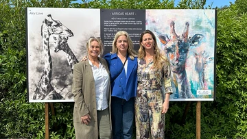 Karin Holmström och Jytte Fredholm Ferreira tillsammans med Helena Johnzon Dahl från Peace Parks Foundation Sweden som tog initiativet till deras första möte. De står framför en tavla med ett foto och en målning av av giraffer.