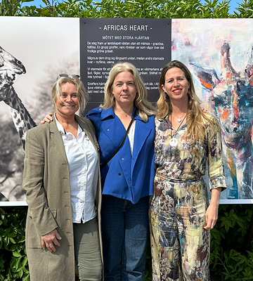 Karin Holmström och Jytte Fredholm Ferreira tillsammans med Helena Johnzon Dahl från Peace Parks Foundation Sweden som tog initiativet till deras första möte. De står framför en tavla med ett foto och en målning av av giraffer.