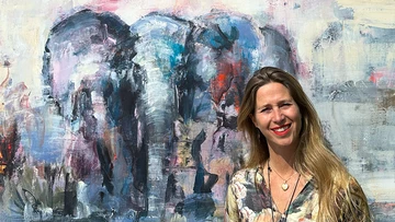Konstnären Karin Holmström framför en målning av en elefant.