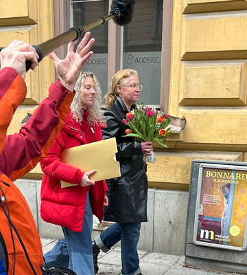 Två personer går och blir filmade på en stadsgata