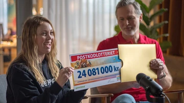 Kvinna drar ut en check från Postkodlotteriet från ett guldkuvert