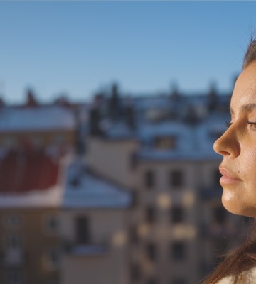 En kvinna i profil i fokus. I bakgrunden syns stadshus i oskärpa.