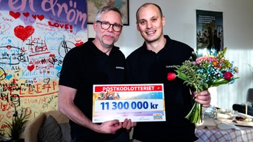 Två personer från Erikshjälpen håller i blommor och en check på 11300000kr