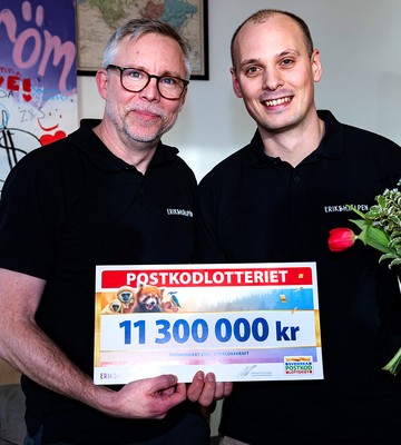 Två personer från Erikshjälpen håller i blommor och en check på 11300000kr